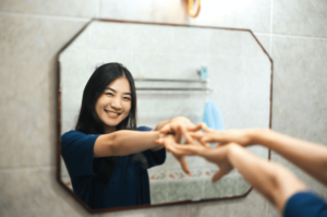 teenager looking in the mirror and finally feeling confident and happy with herself after struggling to heal from trauma, but now she is recovering thanks to trauma counseling in simi valley