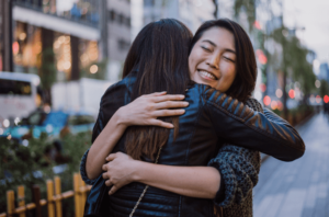 woman hugging her friend and feeling proud of her for showing herself love thanks to anxiety therapy