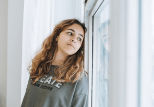 teen looking out the window after being denied love and empathy from her parents, wishing she was in teen therapy in simi valley